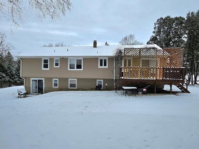 snow covered back of property featuring a wooden deck