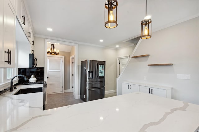 kitchen featuring white cabinetry, light stone countertops, pendant lighting, and stainless steel fridge