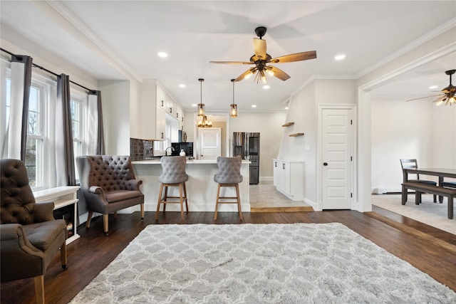 living room with ceiling fan, dark wood-type flooring, and ornamental molding