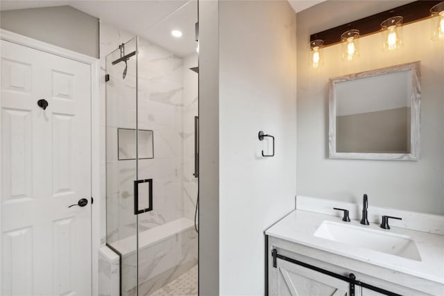 bathroom featuring a shower with shower door and vanity