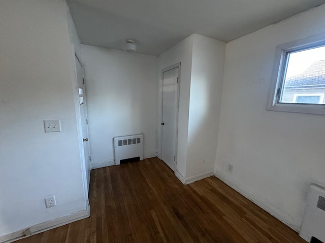 empty room featuring radiator heating unit and dark hardwood / wood-style flooring