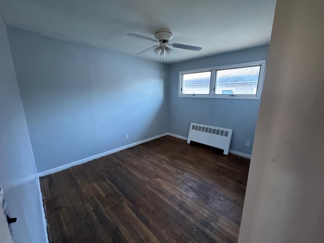 empty room with ceiling fan, radiator heating unit, and dark hardwood / wood-style flooring