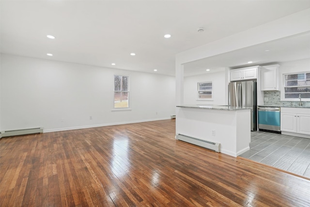 kitchen with appliances with stainless steel finishes, white cabinetry, tasteful backsplash, and a baseboard radiator