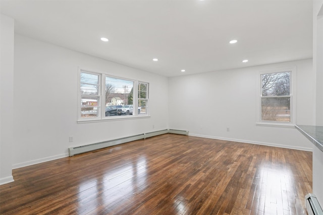 spare room with a baseboard radiator and dark hardwood / wood-style floors