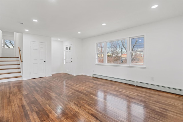 unfurnished living room with a baseboard heating unit and dark wood-type flooring