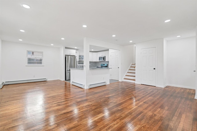 unfurnished living room with a baseboard heating unit and hardwood / wood-style floors