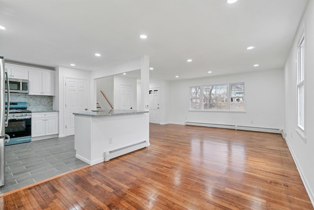 kitchen featuring white cabinets, baseboard heating, appliances with stainless steel finishes, and light hardwood / wood-style floors