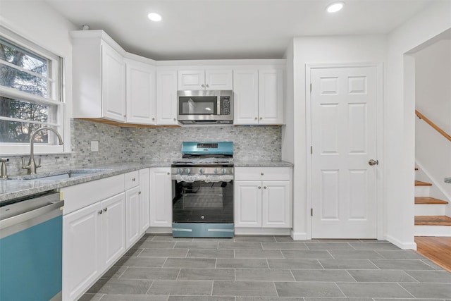 kitchen with stainless steel appliances, white cabinets, and sink