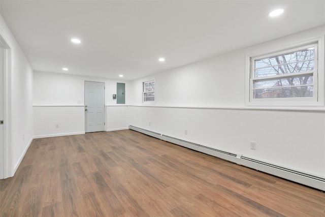 unfurnished room featuring a baseboard heating unit, electric panel, and hardwood / wood-style flooring