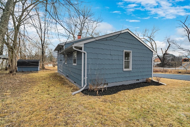 view of property exterior with a lawn and an outdoor structure