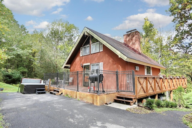 view of property exterior with a jacuzzi and a wooden deck