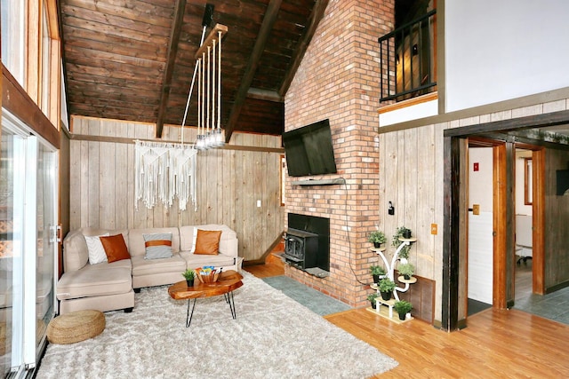 living room featuring beam ceiling, a wood stove, wooden ceiling, hardwood / wood-style floors, and wooden walls