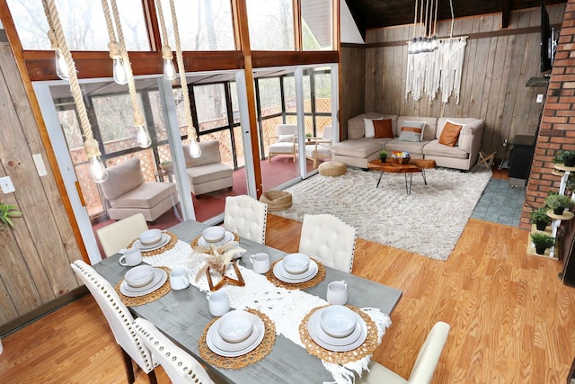 dining area featuring wood-type flooring, an inviting chandelier, and wood walls