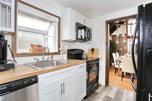 kitchen featuring butcher block counters, white cabinetry, sink, light hardwood / wood-style flooring, and black appliances