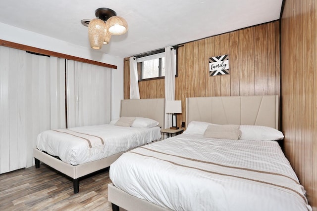 bedroom with hardwood / wood-style floors and wood walls