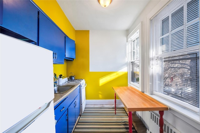 kitchen with plenty of natural light, white appliances, and blue cabinets