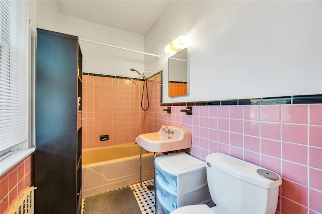 full bathroom featuring sink, tiled shower / bath combo, toilet, and tile walls