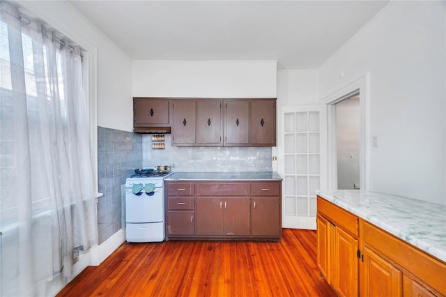 kitchen with tasteful backsplash, dark wood-type flooring, and white gas range oven