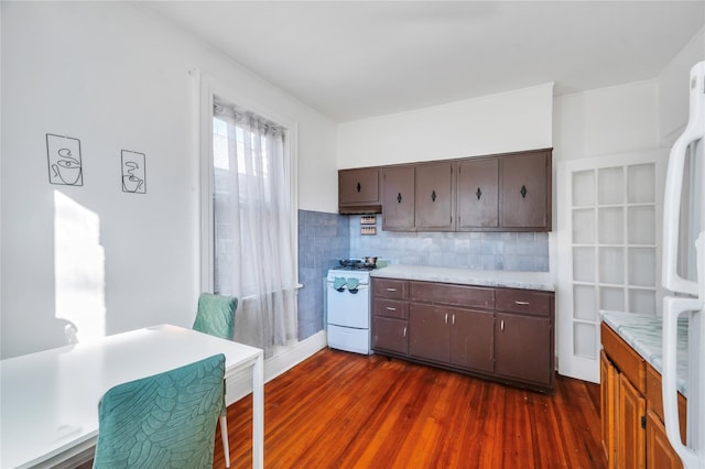 kitchen featuring dark hardwood / wood-style flooring, white gas range oven, fridge, and tasteful backsplash