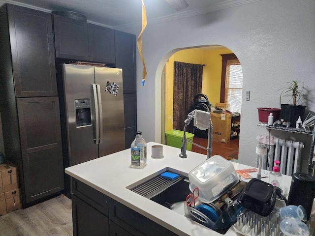 kitchen featuring stainless steel fridge with ice dispenser, radiator heating unit, light hardwood / wood-style floors, and ornamental molding