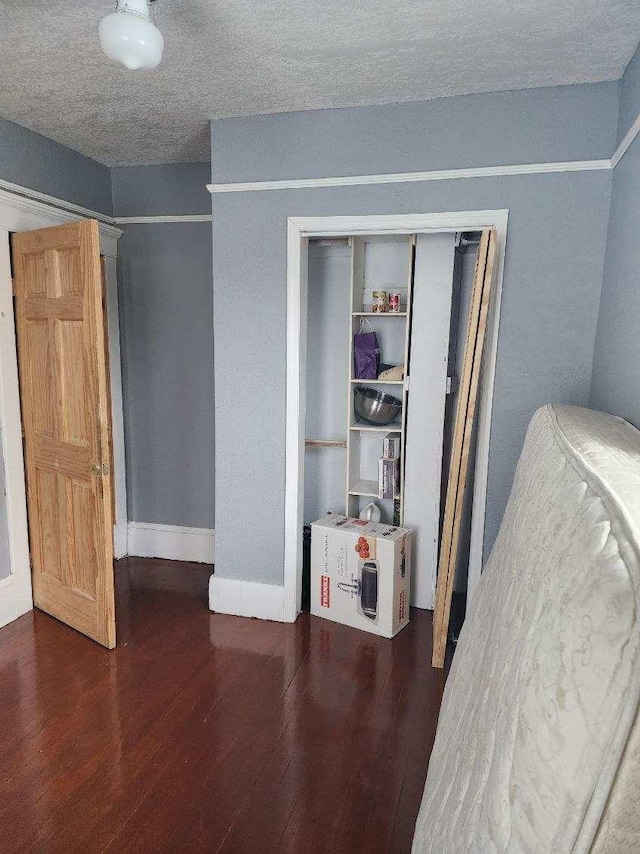 unfurnished bedroom featuring dark wood-type flooring, a textured ceiling, and a closet