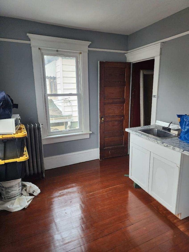 dining area with radiator heating unit, dark wood-type flooring, and sink