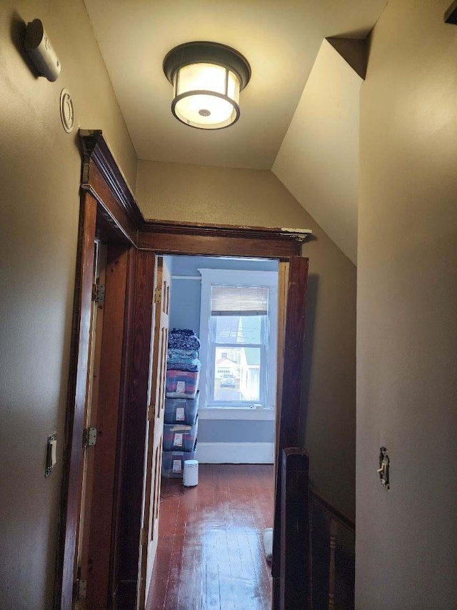 corridor with vaulted ceiling and dark hardwood / wood-style floors