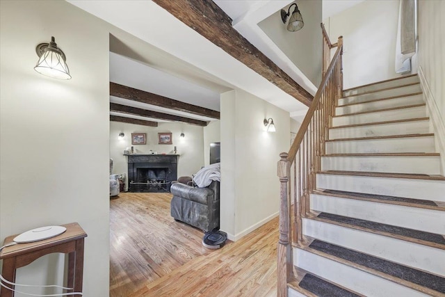 stairs with beamed ceiling and wood-type flooring