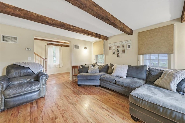 living room featuring beamed ceiling, a healthy amount of sunlight, and light hardwood / wood-style flooring