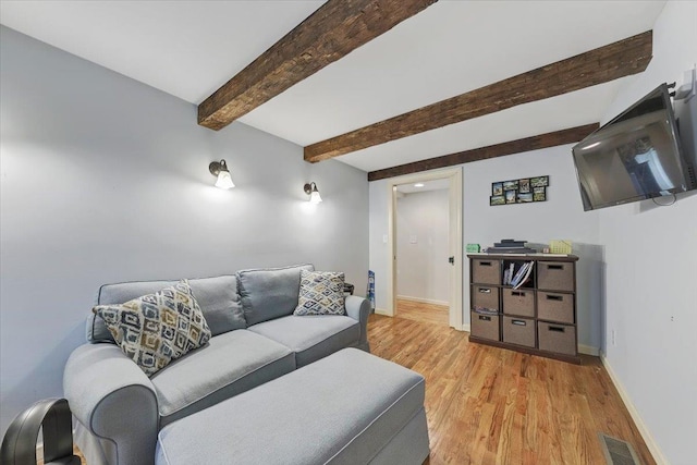 living room featuring beam ceiling and light hardwood / wood-style flooring