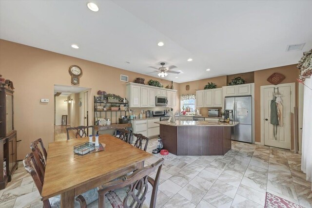 kitchen with white cabinets, ceiling fan, light stone counters, and appliances with stainless steel finishes