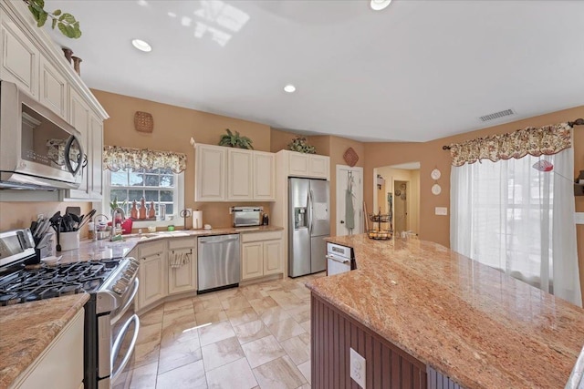 kitchen featuring a center island, light stone counters, and stainless steel appliances