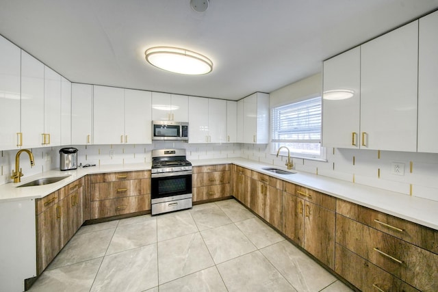 kitchen featuring backsplash, white cabinetry, sink, and appliances with stainless steel finishes