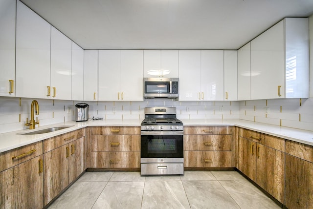 kitchen with backsplash, sink, white cabinets, and stainless steel appliances