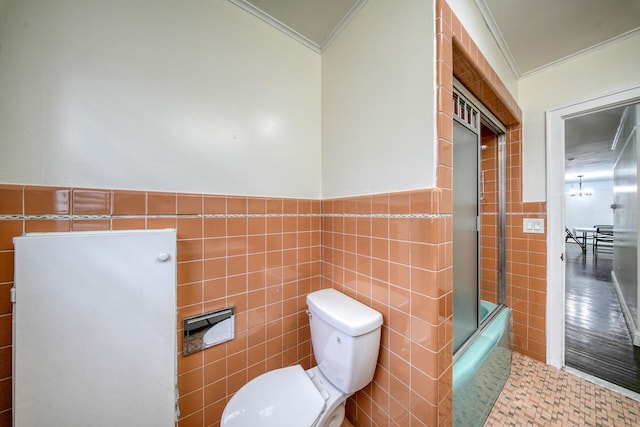 bathroom with crown molding, bath / shower combo with glass door, tile walls, and toilet