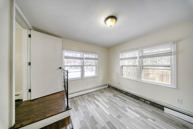 spare room with a healthy amount of sunlight, light hardwood / wood-style flooring, and a baseboard heating unit