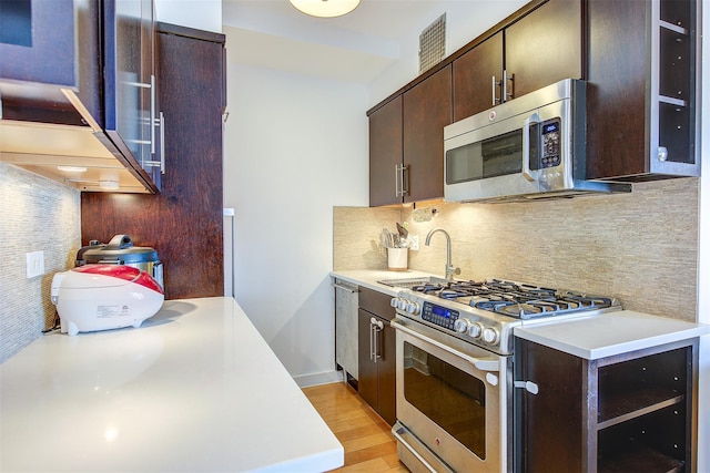 kitchen with sink, backsplash, light hardwood / wood-style floors, dark brown cabinets, and appliances with stainless steel finishes