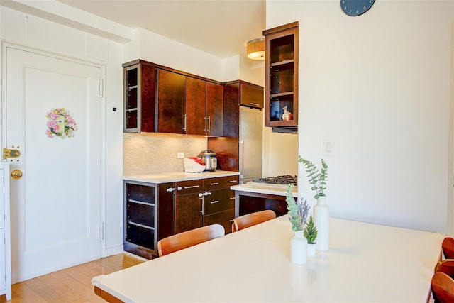 kitchen with stainless steel gas cooktop, tasteful backsplash, wine cooler, dark brown cabinets, and light wood-type flooring