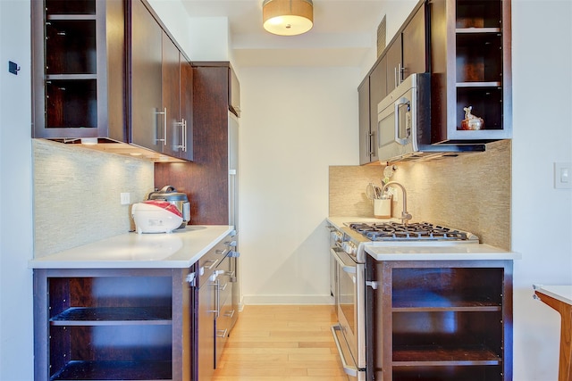 kitchen featuring decorative backsplash, dark brown cabinetry, light wood-type flooring, and gas range