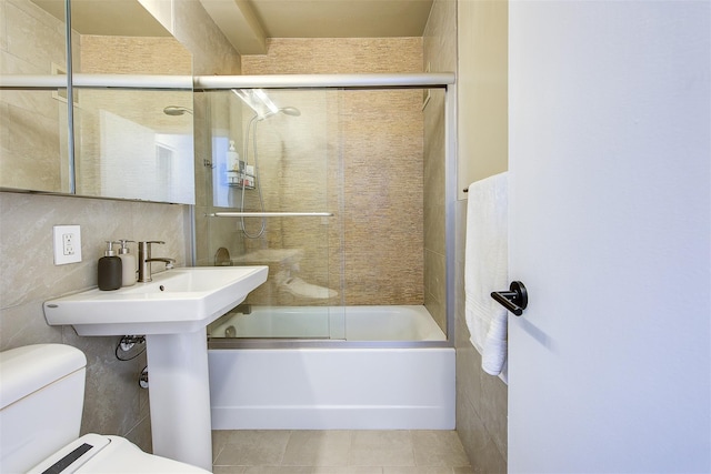 bathroom with tile patterned flooring, toilet, tile walls, and bath / shower combo with glass door