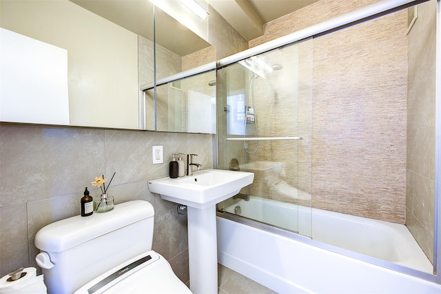 bathroom featuring backsplash, toilet, shower / bath combination with glass door, and tile walls