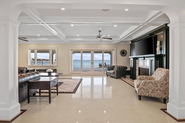 living room with a water view, ceiling fan, ornamental molding, a premium fireplace, and beamed ceiling