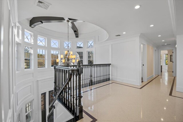 hallway with a towering ceiling and crown molding