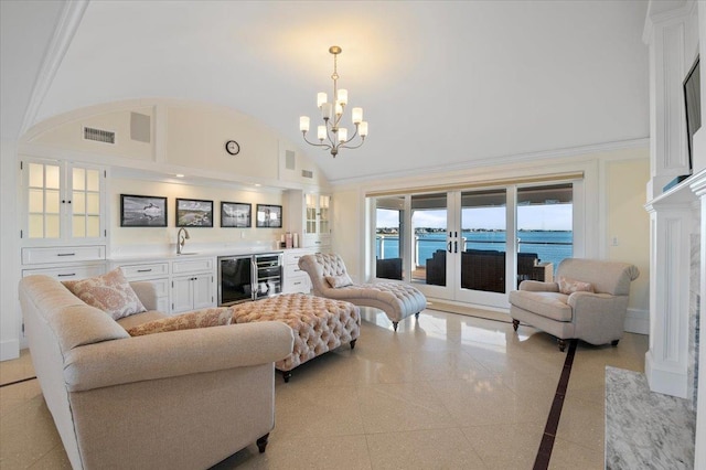 living room featuring sink, beverage cooler, a towering ceiling, a chandelier, and a water view