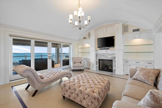 living room featuring built in features, a water view, vaulted ceiling, and a notable chandelier