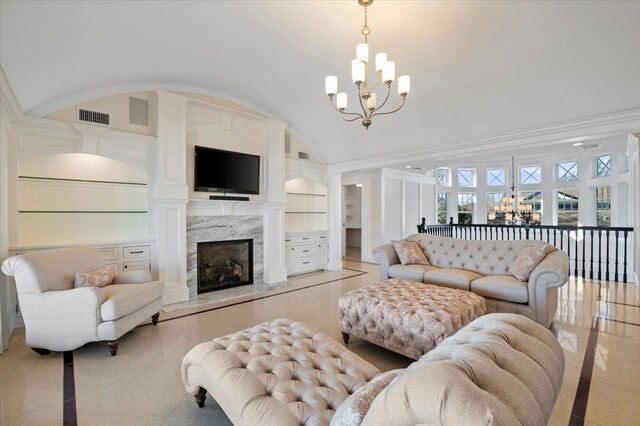 living room with a chandelier, built in features, lofted ceiling, and a high end fireplace