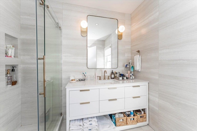 bathroom with vanity, an enclosed shower, and tile walls