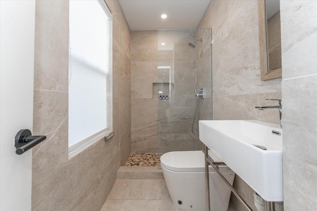 bathroom featuring sink, toilet, tiled shower, and tile walls