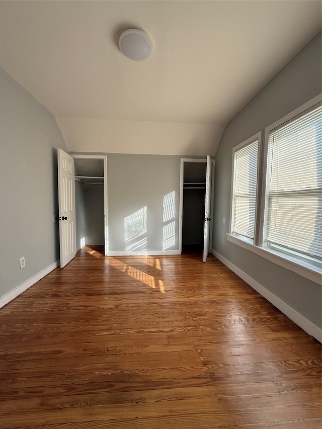 unfurnished bedroom featuring vaulted ceiling, a closet, and wood-type flooring