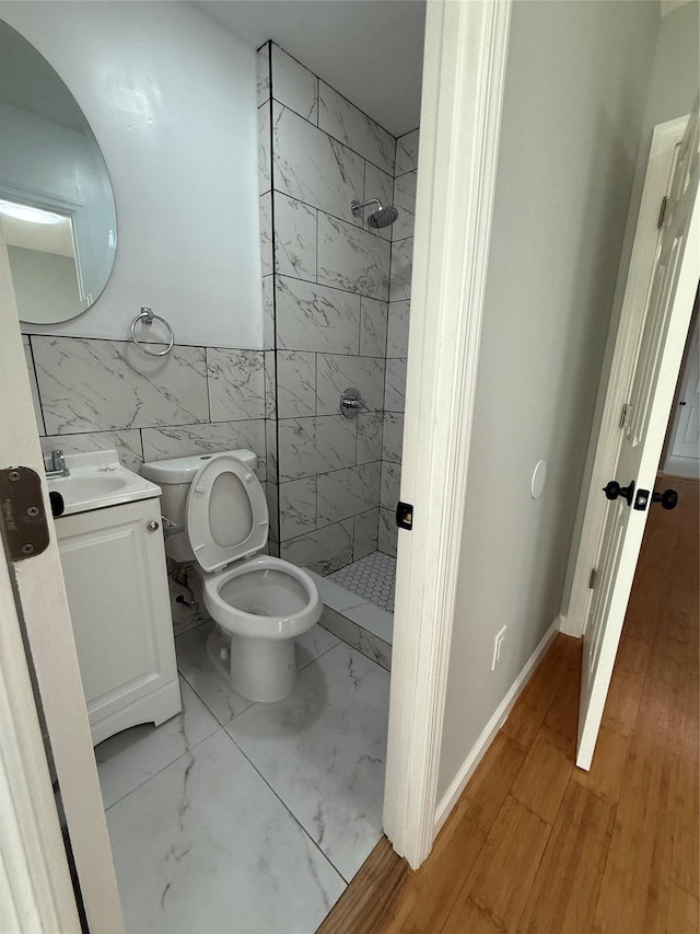 bathroom with vanity, toilet, tile walls, and a tile shower